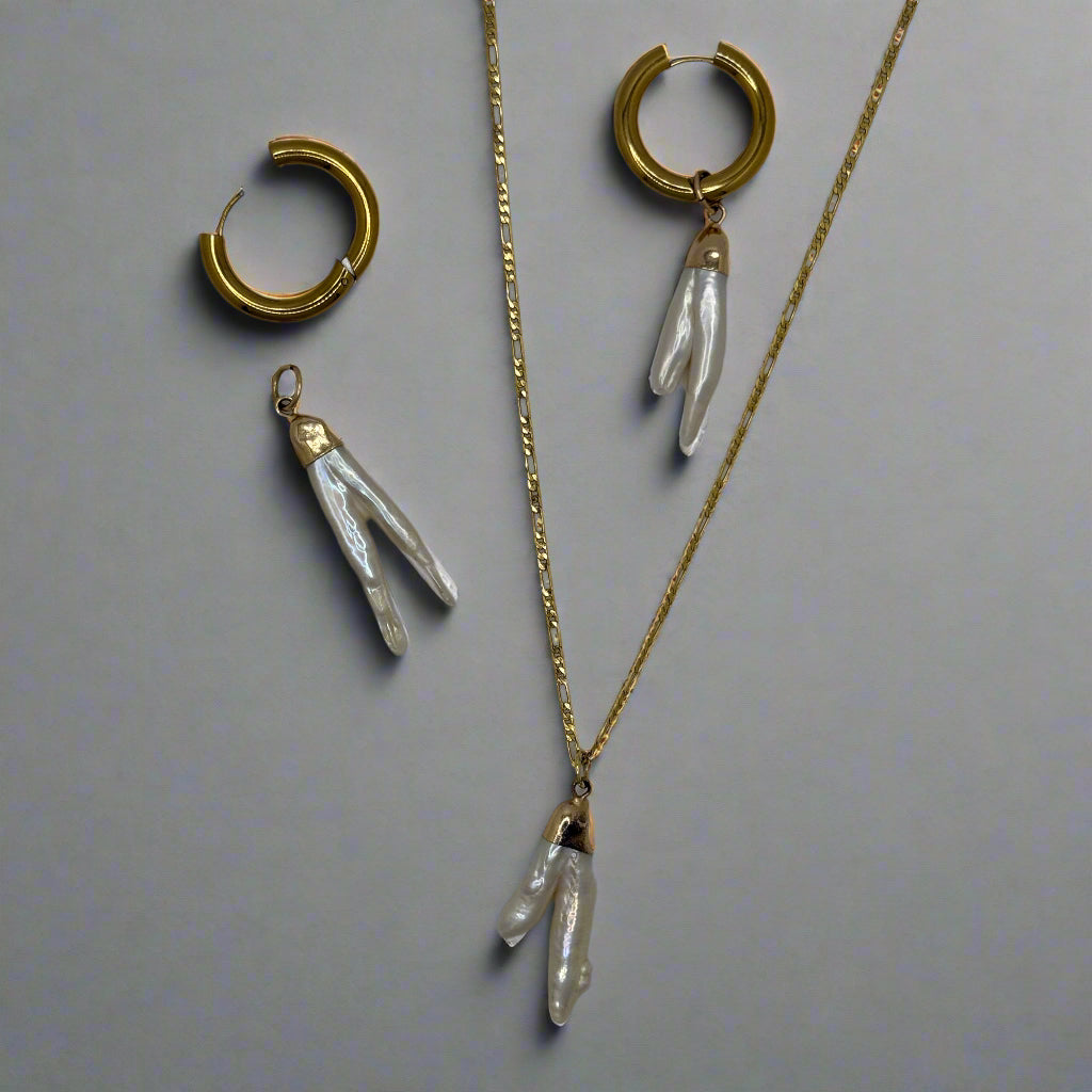 Gold and pearl jewelry pieces on a light gray background