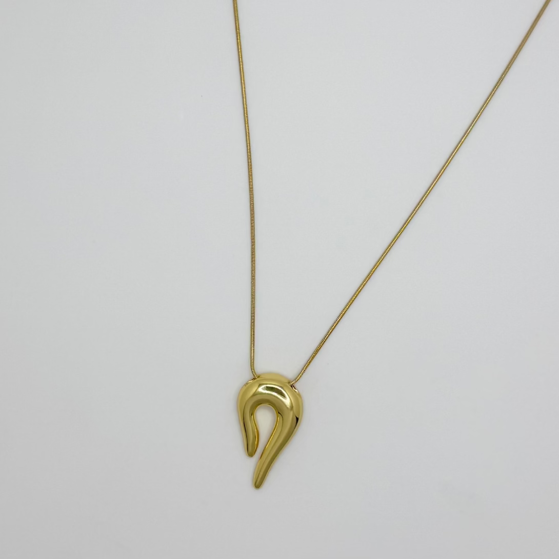 Gold necklace with a unique pendant on a light gray background